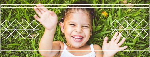 Child laughing in grass with geometric pattern 